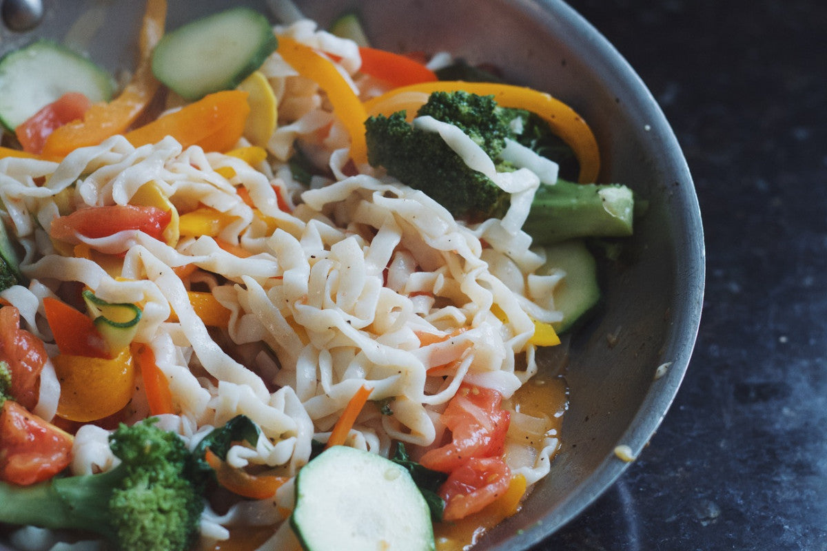 Round blue gray bowl with fresh veggies including broccoli, zucchini, peppers and grated mozzarella.