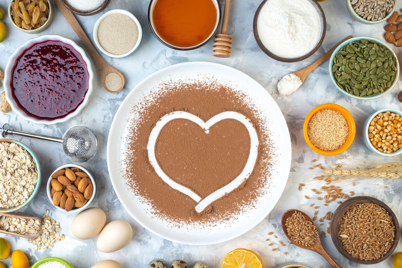 Top view heart imprint in powdered cocoa on white plate bowls with various ingredients on table.